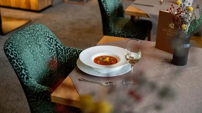 Ein Teller Suppe mit einem Glas Wein auf einem gedeckten Restauranttisch