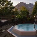 Whirlpool auf Holzterrasse mit Bergblick und Pflanzen bei Sonnenuntergang