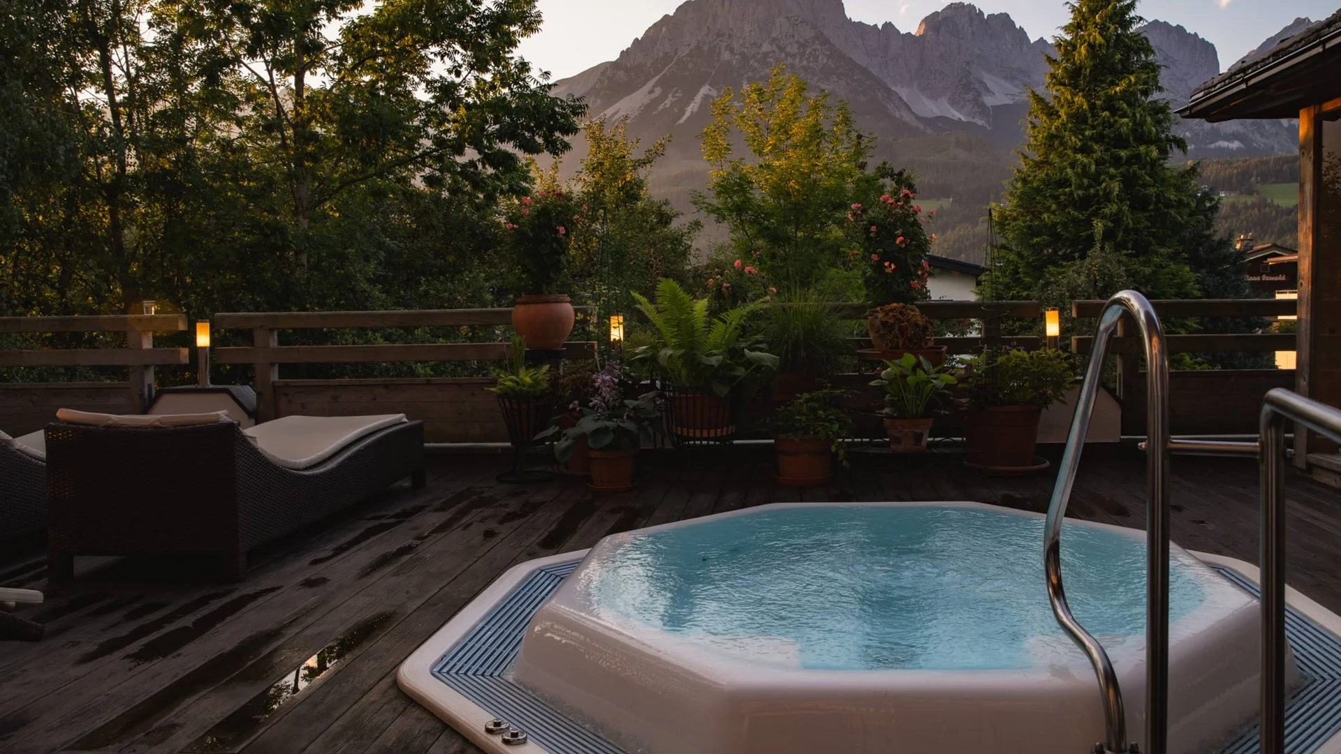 Whirlpool auf Holzterrasse mit Bergblick und Pflanzen bei Sonnenuntergang