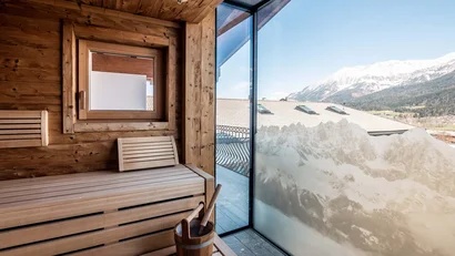 Sauna mit Holzinneneinrichtung und Bergblick durch großes Fenster