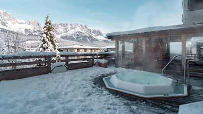 Whirlpool auf schneebedeckter Terrasse mit Blick auf Berglandschaft