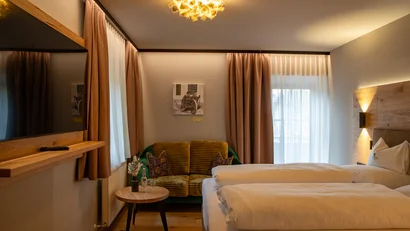Gemütliches Hotelzimmer mit Doppelbett, Sofa und warmem Licht